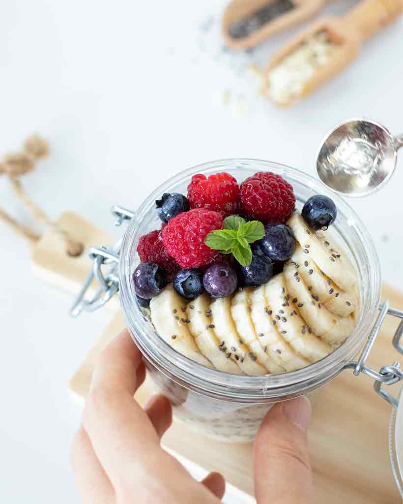 Hand holding the best low-calorie overnight oats with fruit with a spoon