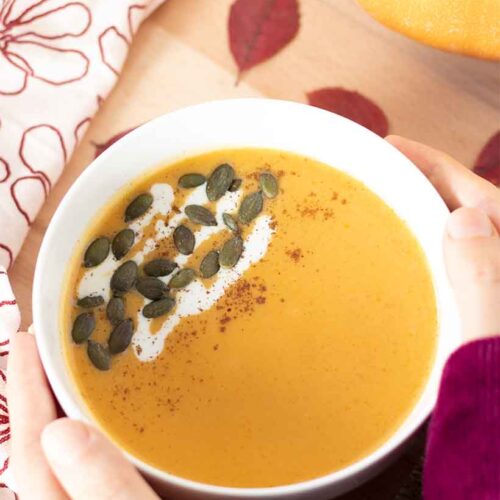 Ceamy vegan butternut squash soup drizzled with coconut milk and topped with pepitas in a bowl. Easy Thanksgiving side dish or starter recipe without roasting.