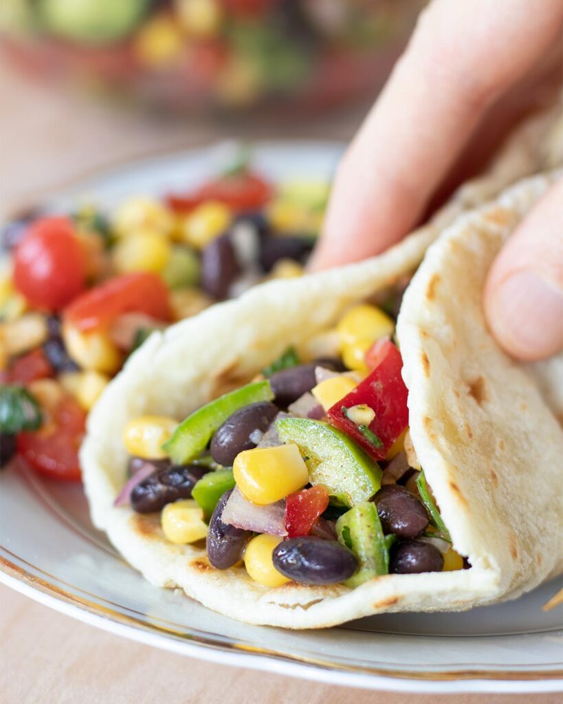 Healthy Mediterranean black bean and corn salad in a homemade torilla on a plate