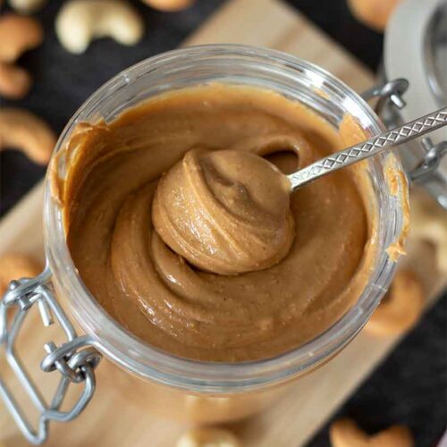 Homemade cashew butter (no oil) in a jar with a spoon. Protein-rich veegan spread for snack or breakfast.