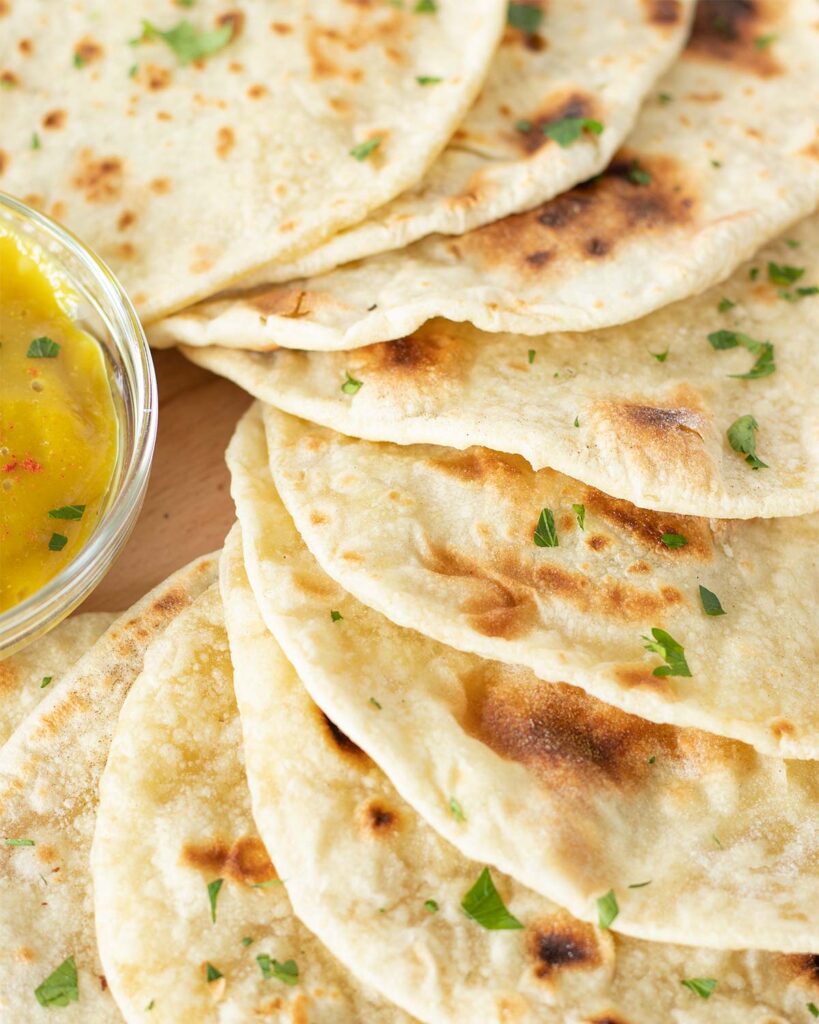 Thin and soft homemade flour tortillas with vegan cheese sauce sprinkled with chopped parsley leaves