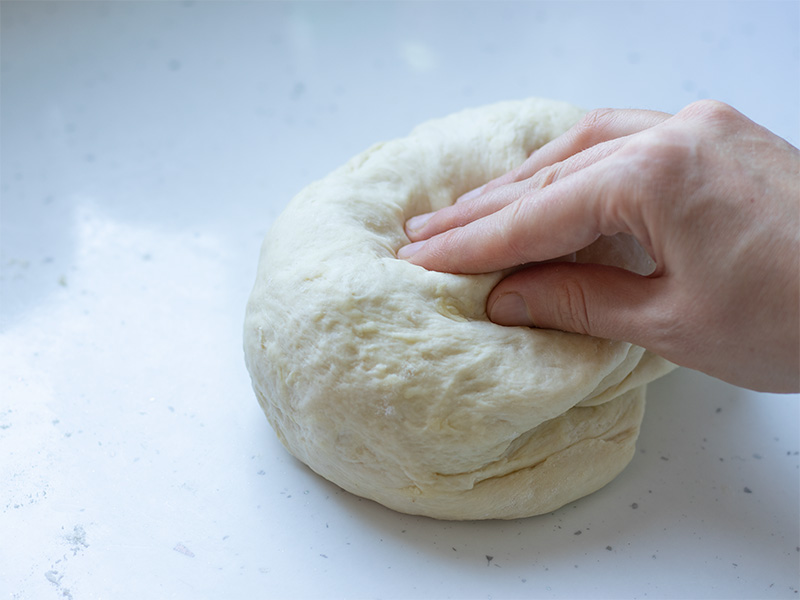 Female hand kneading dough without yeast on white surface