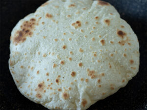 Thin and soft DIY tortilla without baking soda or yeast is cooking in a non stick frying pan on stovetop