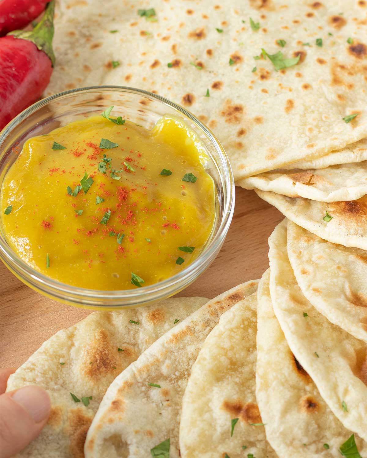 Simple homemade flour tortillas without yeast, baking powder, lard, or shortening with a small bowl of creamy cheese sauce and fresh red and green peppers on wooden table