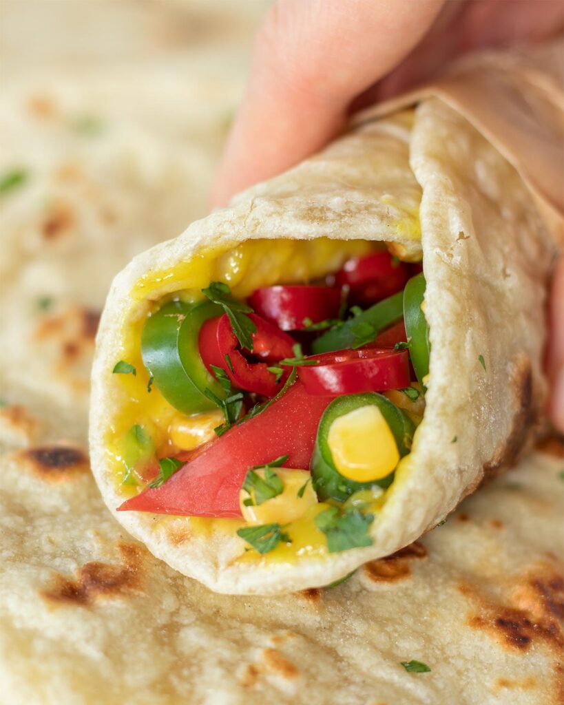 Homemade flour tortillas without baking soda stuffed with vegan cheese sauce and chopped fresh vegetables