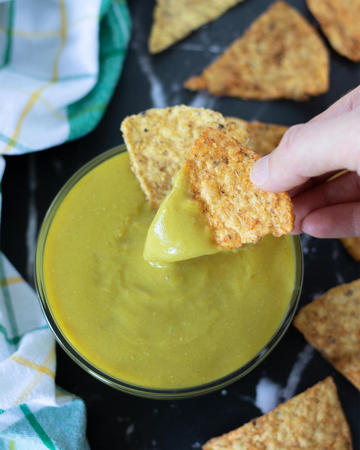 Best recipe vegan cheese sauce in a bowl with hand holding corn chips