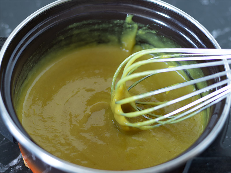 Nut-free and fat-free homemade cheese sauce in a saucepan with a whisk
