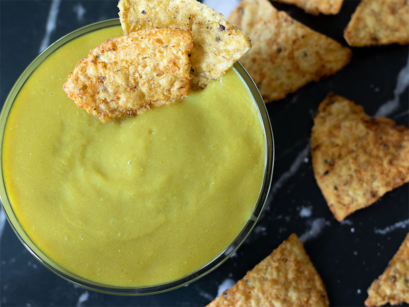 Simple vegan scheese sauce for pasta, pizza, lasagna, broccoli, nachos in a bowl with corn chips
