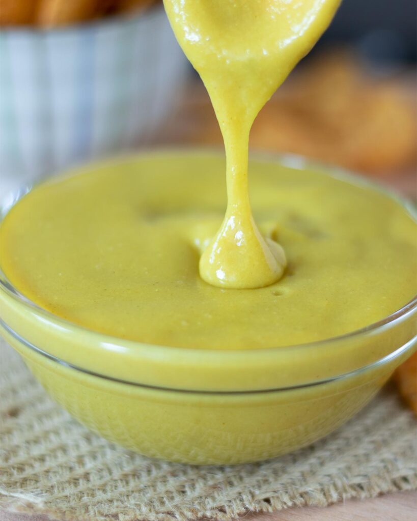 Creamy vegan cheese sauce with nutritional yeast (no cashews) in a bowl with a spoon