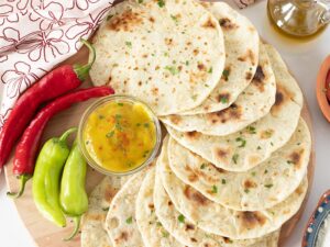 Simple DIY flour tortillas with fresh red and green peppers and homemade cheese sauce on wooden background