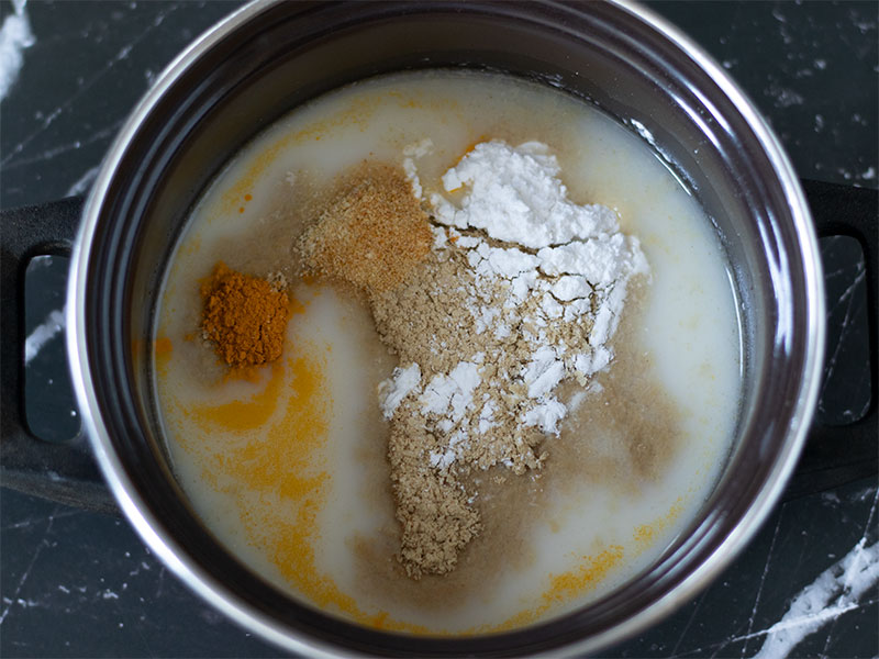 Oat milk, nutritional yeast, tapioca starch, salt and spices in a small saucepan for preparing homemade vegan cheese sauce