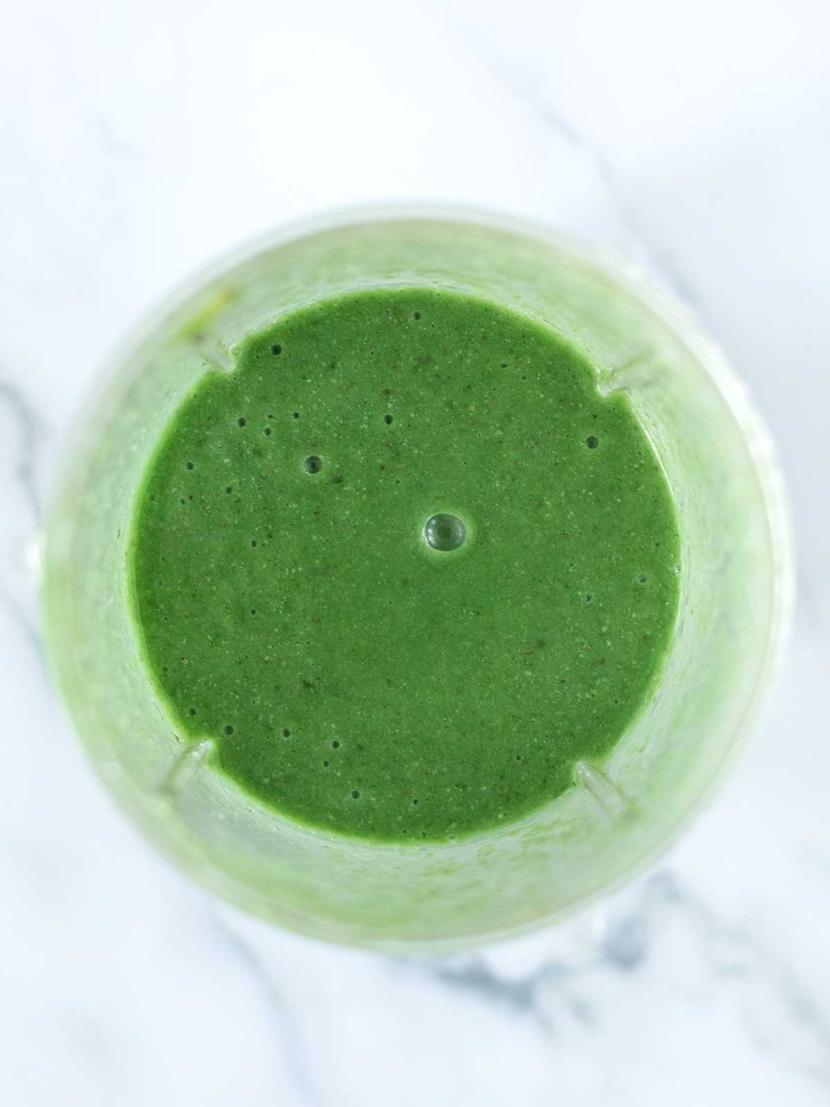 Creamy green detox smoothie with coconut water in a blender