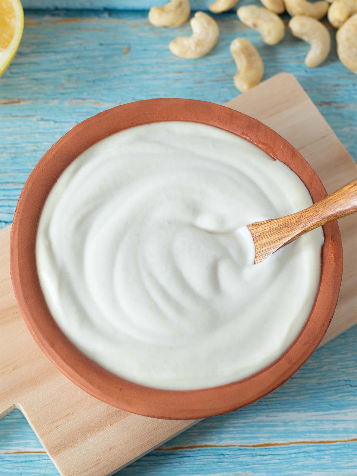 Creamy plant-based cashew-based dip in a bowl with wooden spoon used as a substitute for sour cream