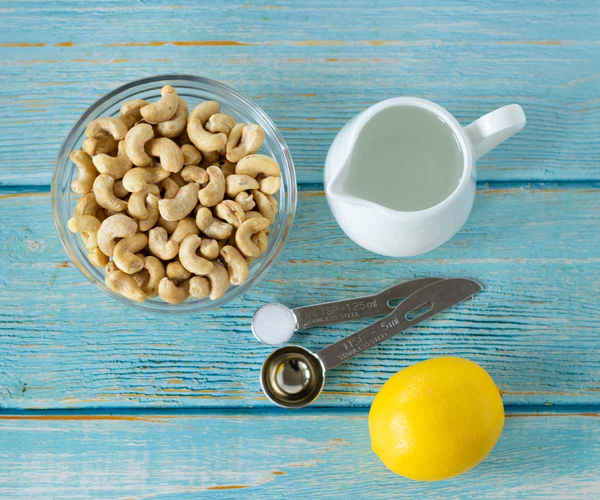 Plant-based ingredients for making simple homemade vegan sour cream: raw cashews, lemon juice, apple cider vinegar, salt, and water.
