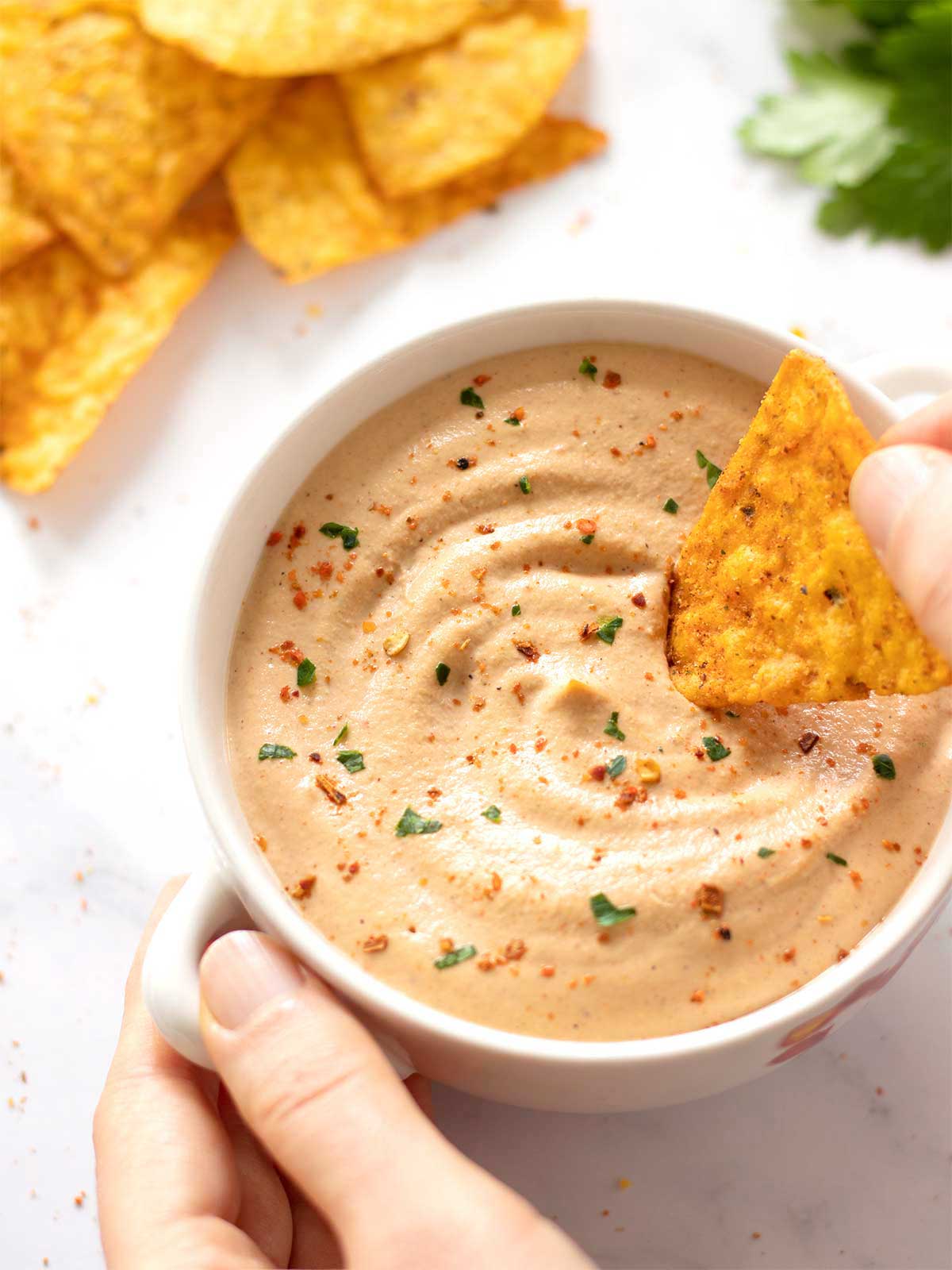 Creamy homemade vegan queso dip in a bowl with corn chips