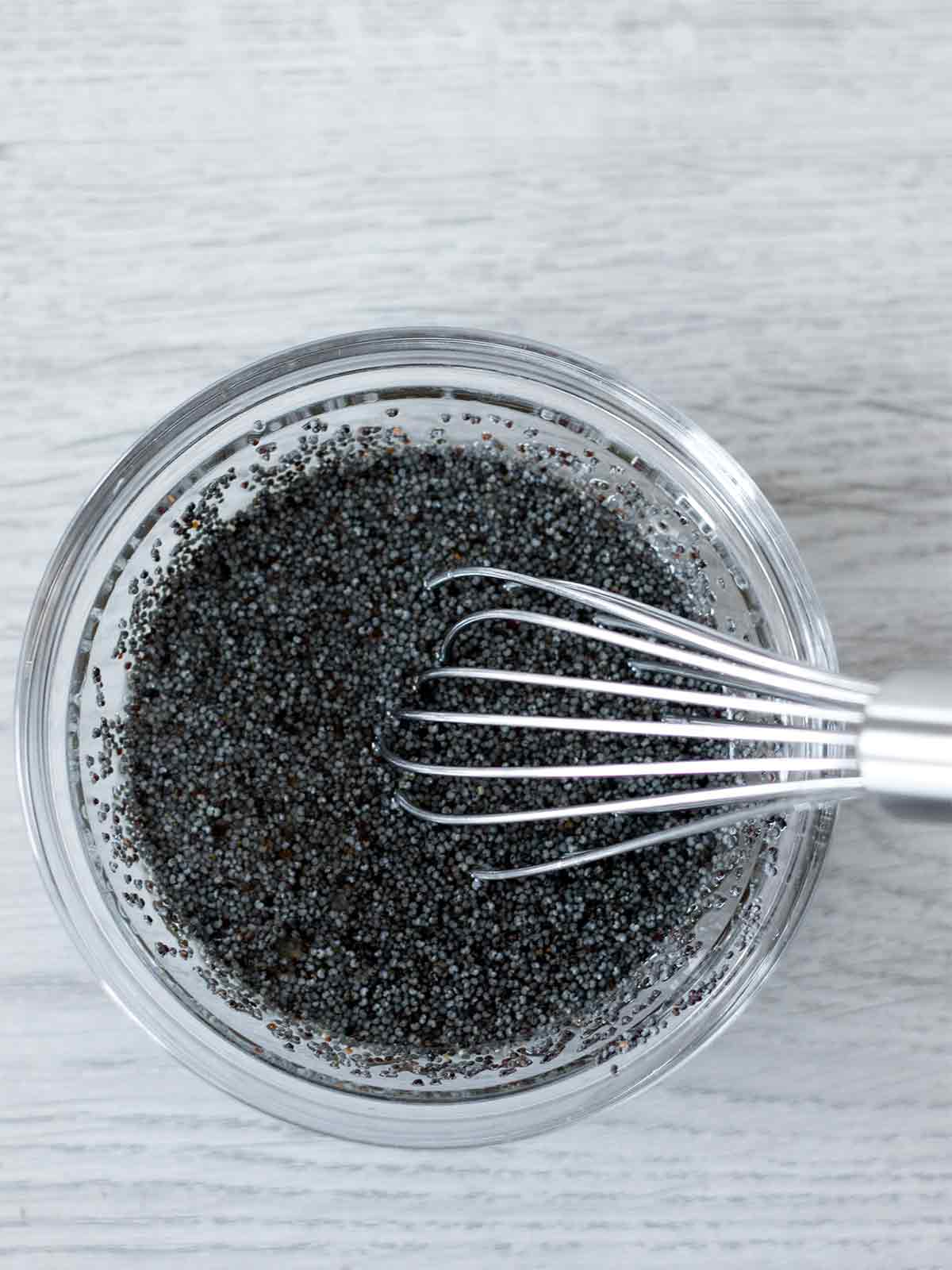 Simple homemade lemon maple poppy seed dressing in a small bowl with a whisk