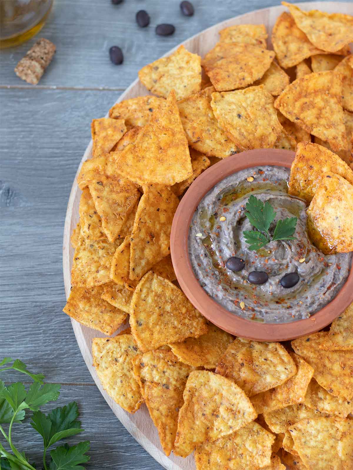 Vegan homemade black bean hummus garnished with red pepper flakes and fresh parsley with corn chips