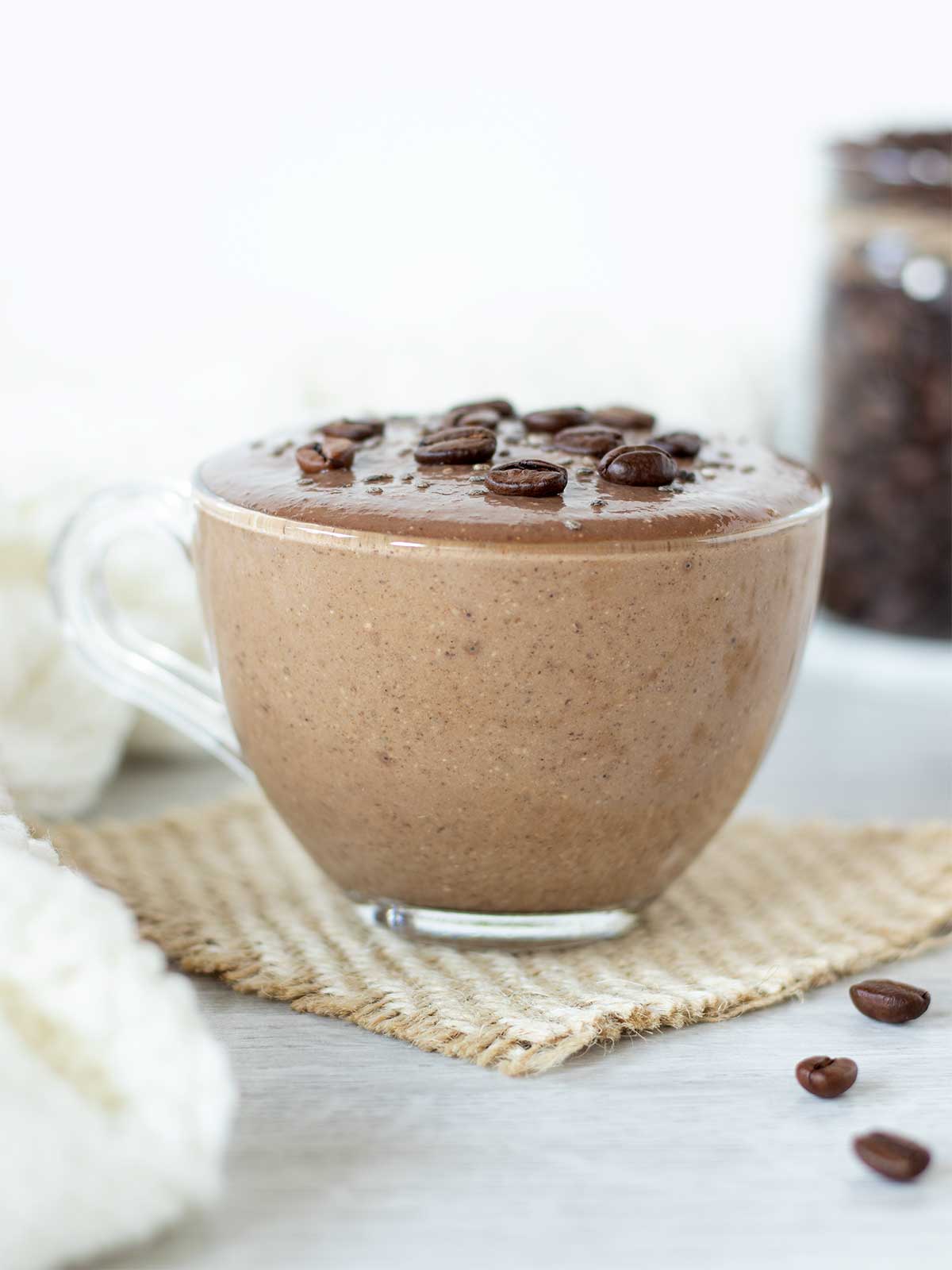 Cold chocolate caffeine smoothie in a glas cup with coffee beans and woolen scarf