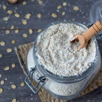 Homemade oat flour made from rolled oats in a glass jar with wooden spoon