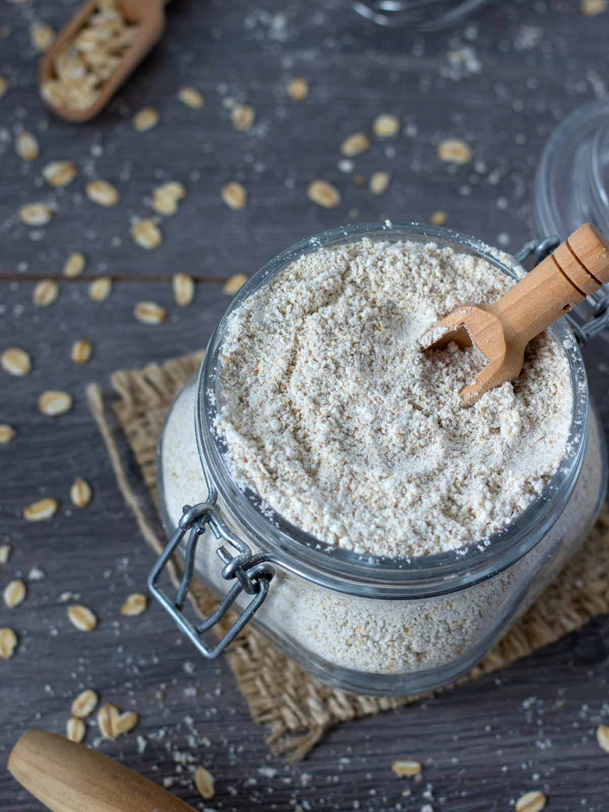 Homemade whole-grain flour made from ground rolled oats in a glass jar with wooden spoon