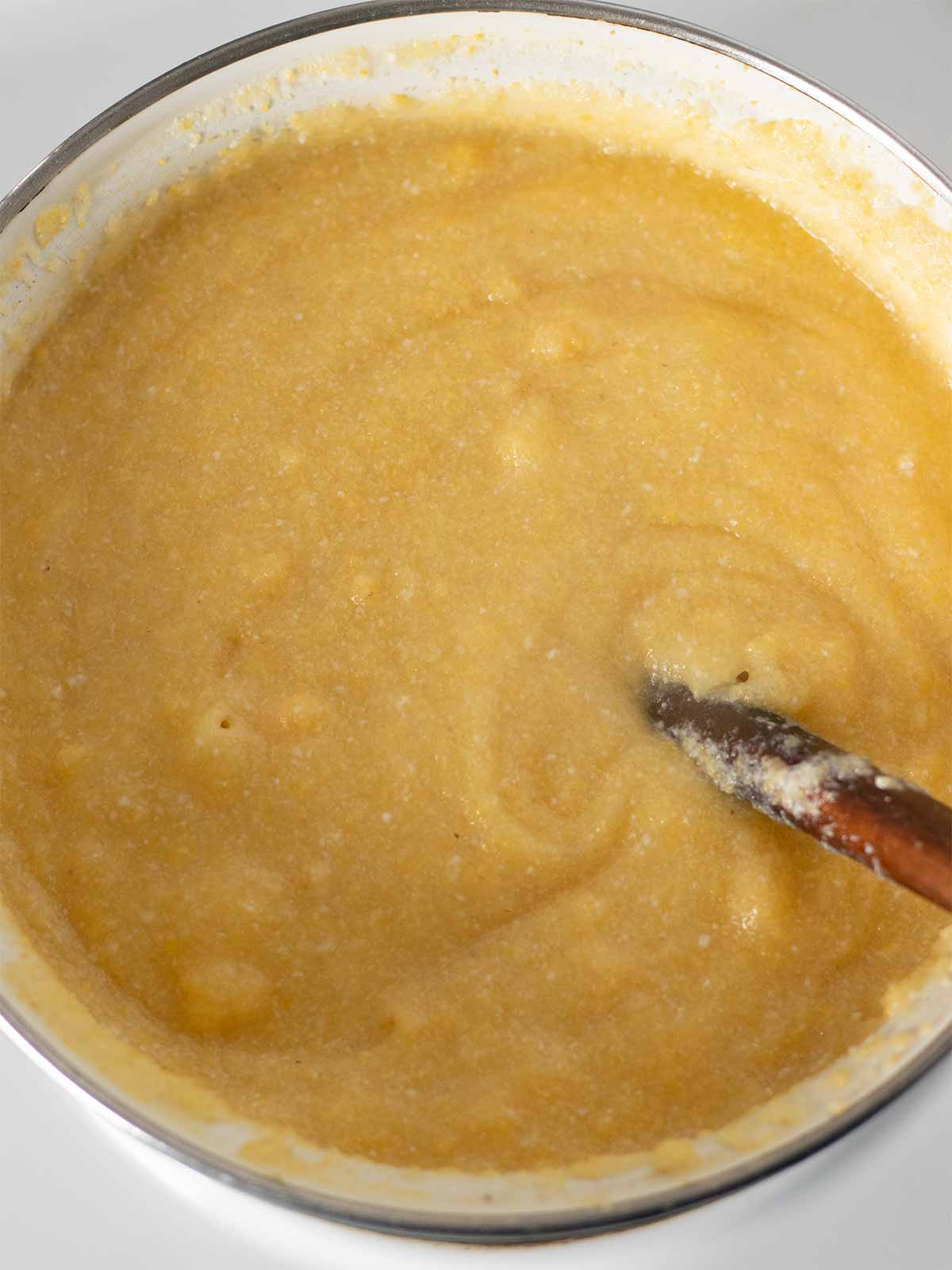 Creamy polenta in a saucepan with wooden spoon