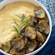Creamy mushroom polenta dish garnished with fresh rosemary and vegan parmesan cheese for savory breakfast, appetizer, side dish, lunch or dinner