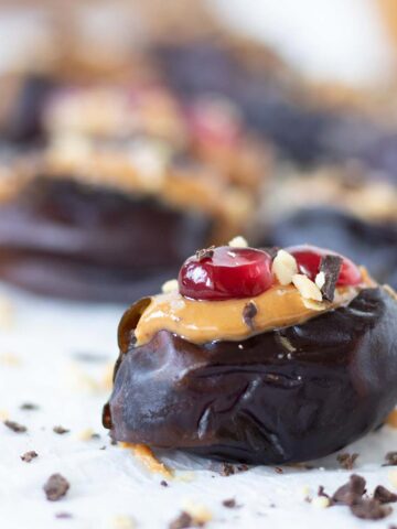 Peanut butter stuffed dates topped with dark chocolate and pomegranate seeds as an easy no-bake dessert or snack