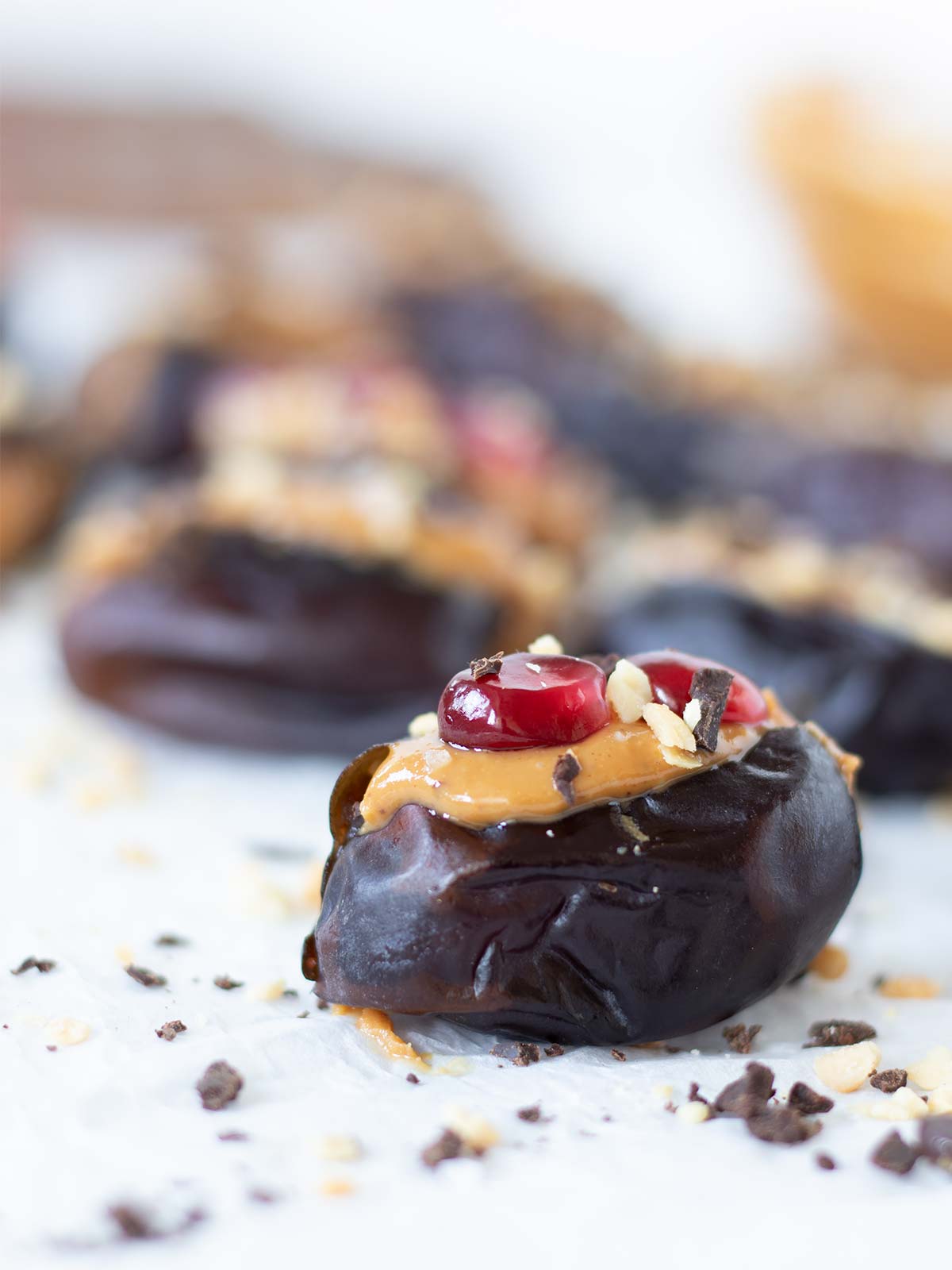 Peanut butter stuffed dates topped with dark chocolate and pomegranate seeds as an easy no-bake dessert or snack