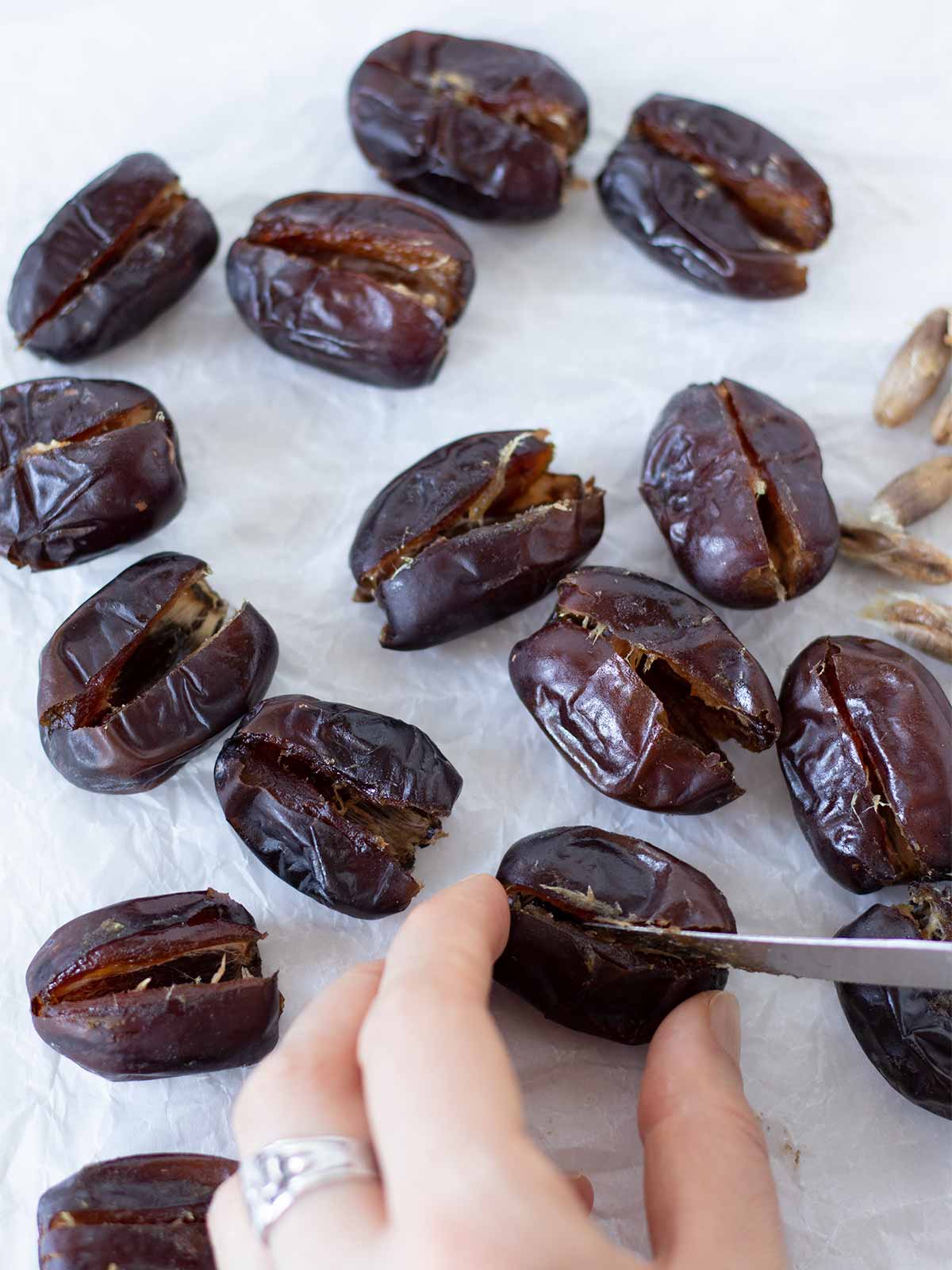 Female hand slicing dates for stuffing them with peanut butter