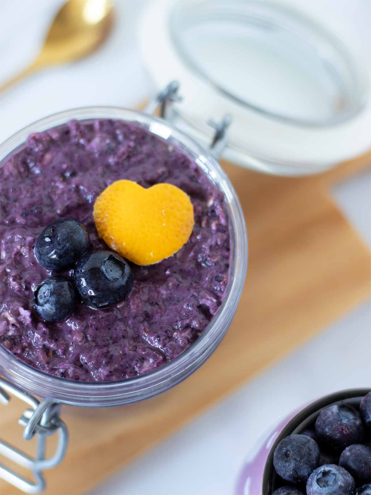 Healthy blueberry overnight oats in a jar decorated with carved lemon peel heart
