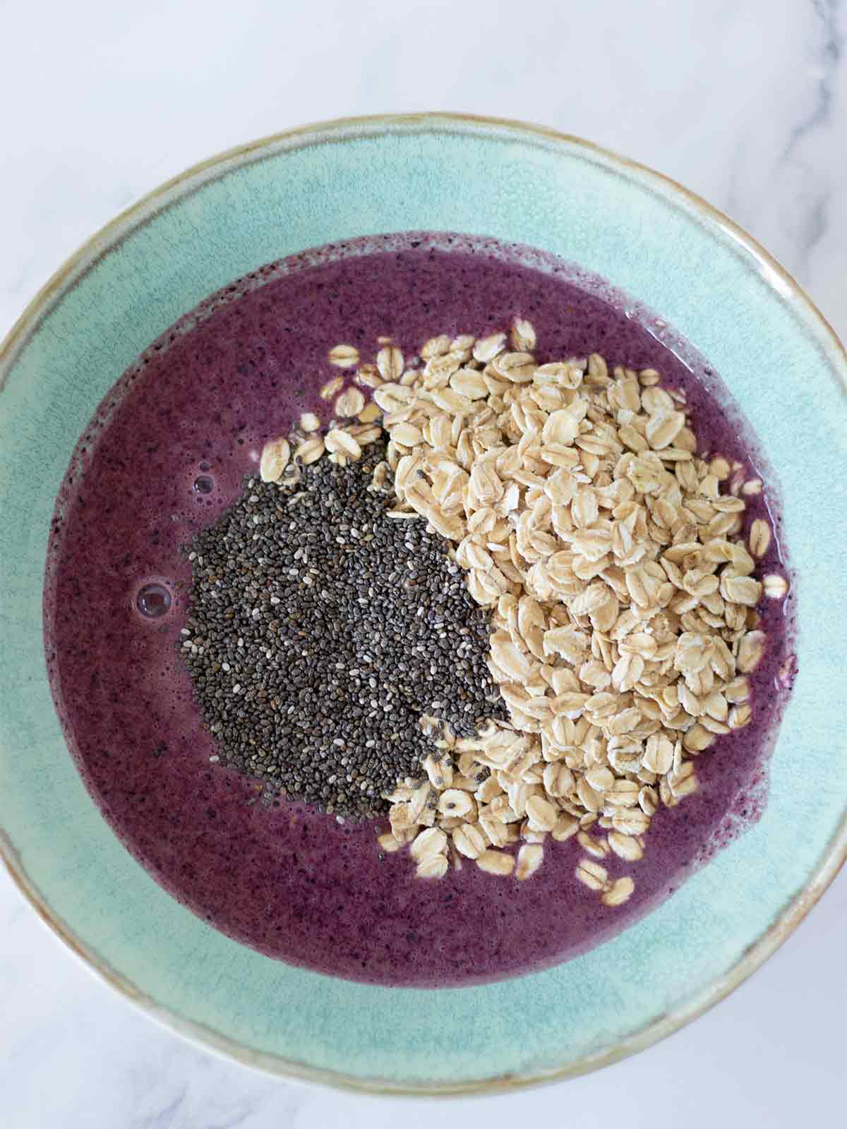 Blueberry lemon milk mixed with rolled oats and chia seeds in a dish for preparing vegan overnight oats