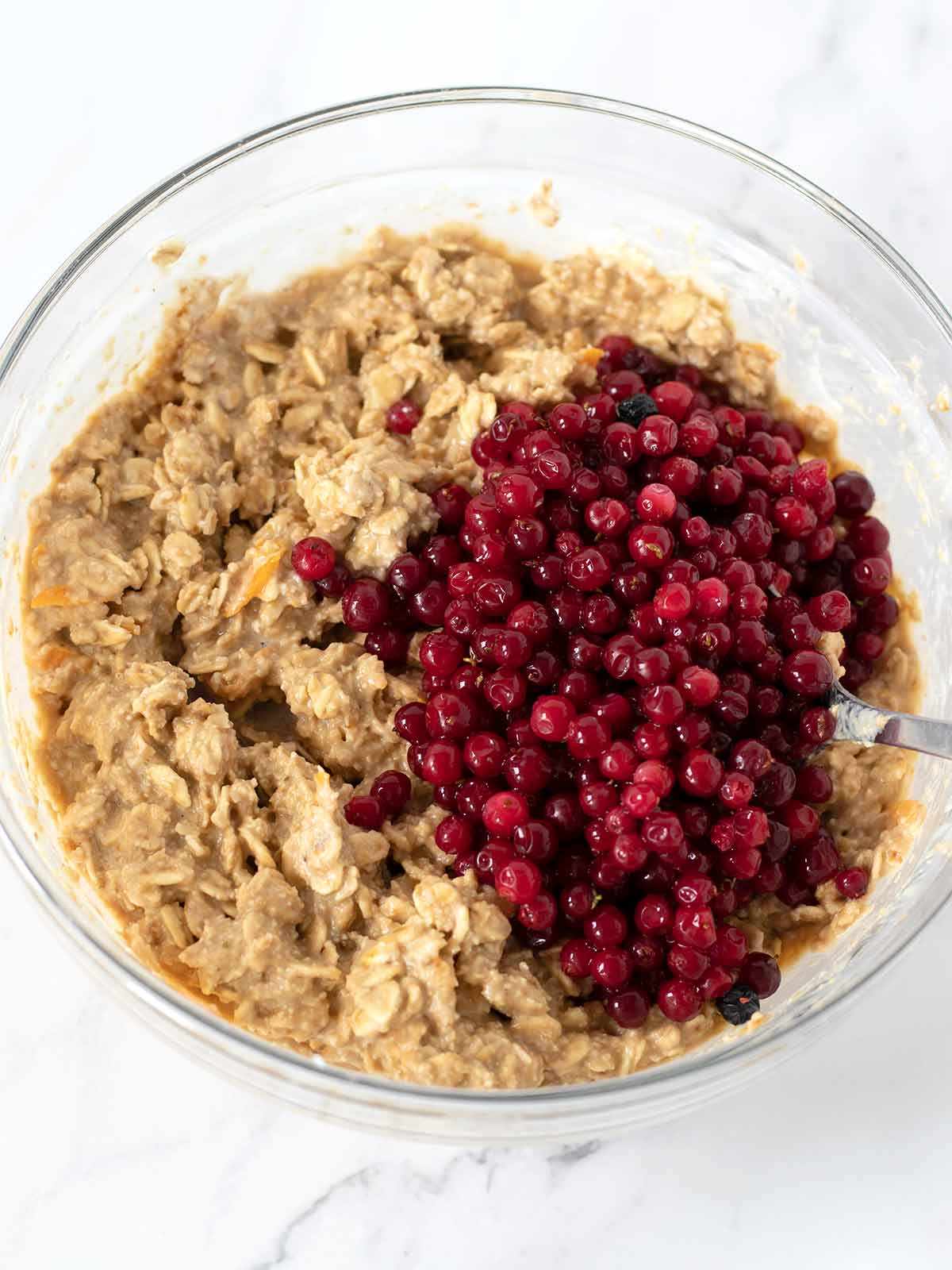 Frozen wild cranberries in a bowl with homemade oatmeal dough for baking healthy low-calorie sweet snacks