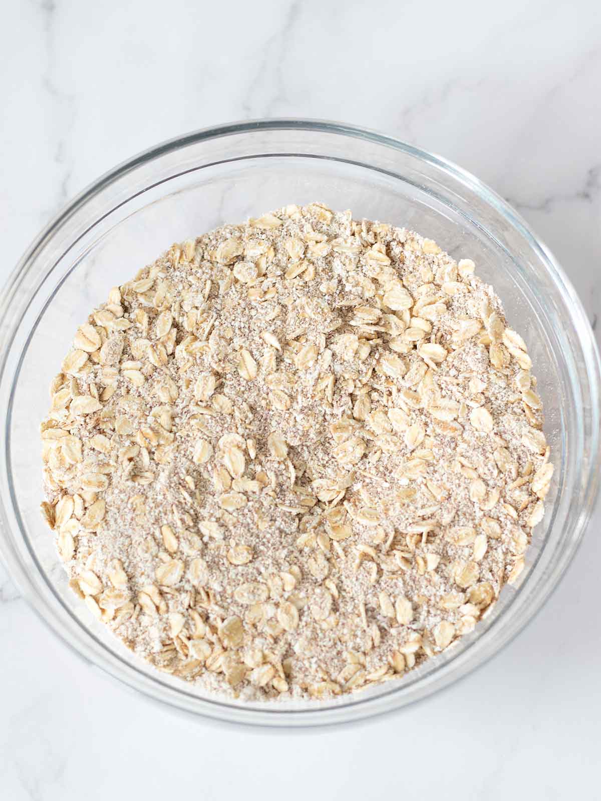 Rolled oats, coconut suagr, and oat flour mixed in a bowl