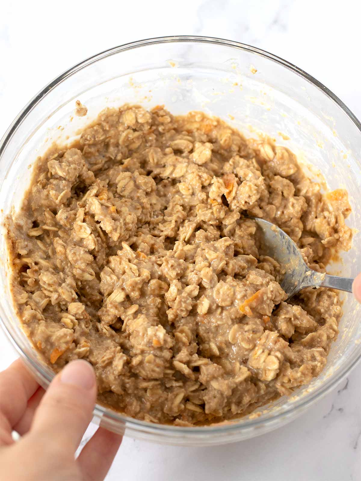 Healthy gluten-free dough in a glass bowl with a spoon for making vegan oatmeal cookies