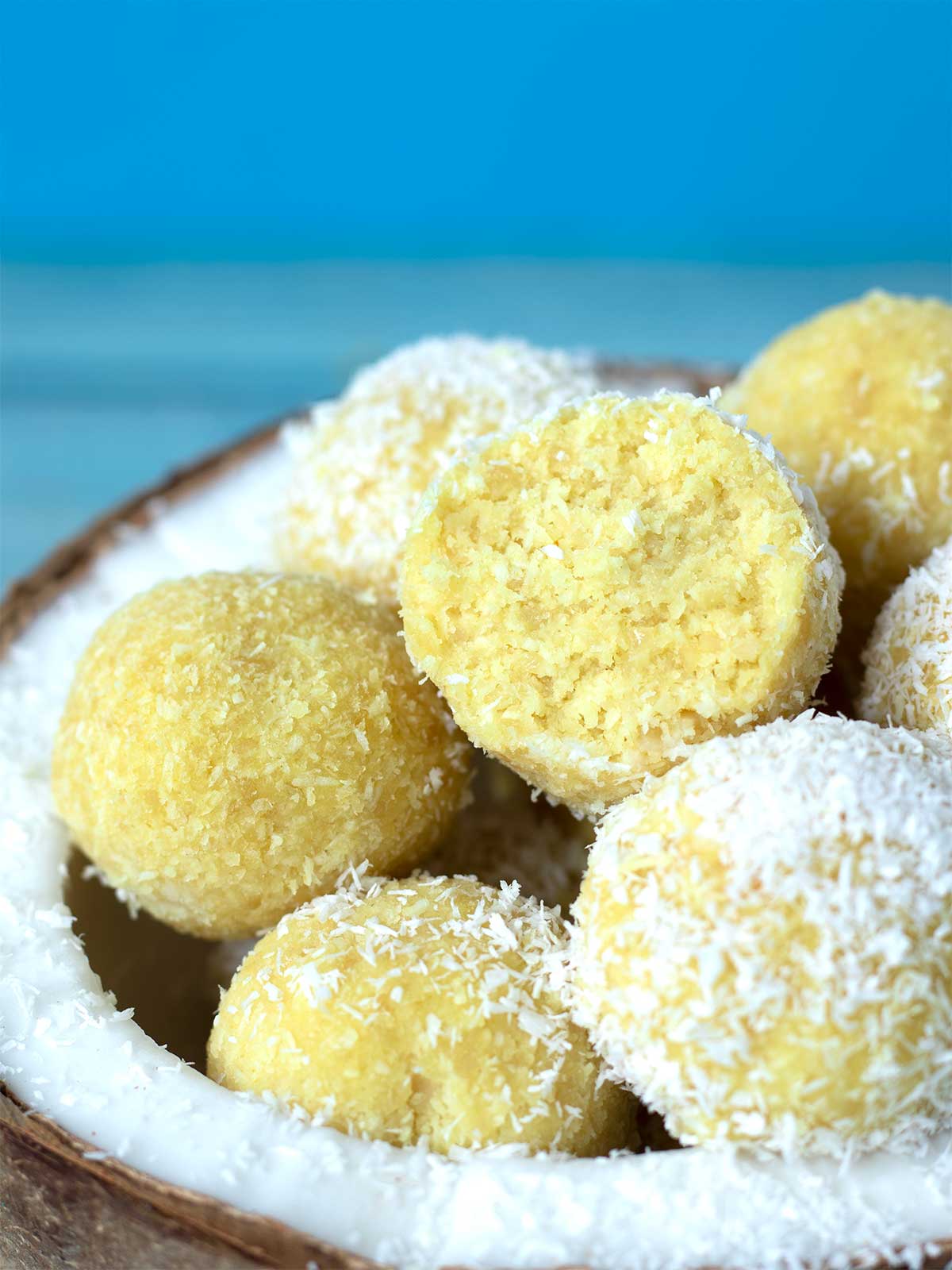 Raw vegan protein bites in a cococnut shell with blue background