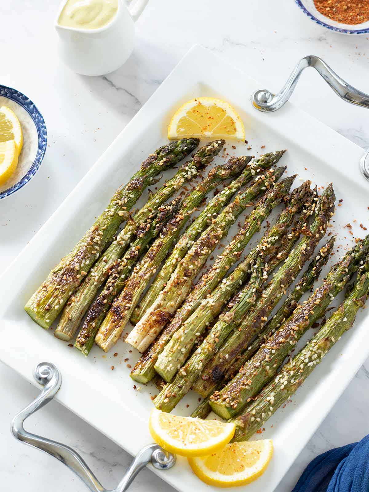Asparagus side dish sprinkled with sesame seeds and red pepper flakes and drizzled with freshly squeezed lemon juice