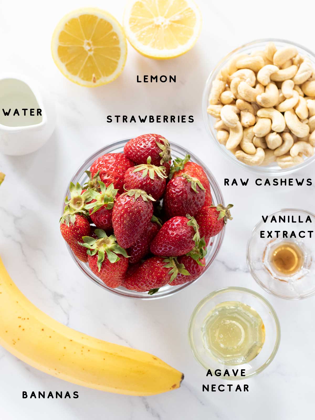 Simple plant-based ingredients for preparing easy cheesecake salad with fresh summer fruit: strawberries, bananas, raw cashews, lemon juice, agave nectar, vanilla extract, and water.