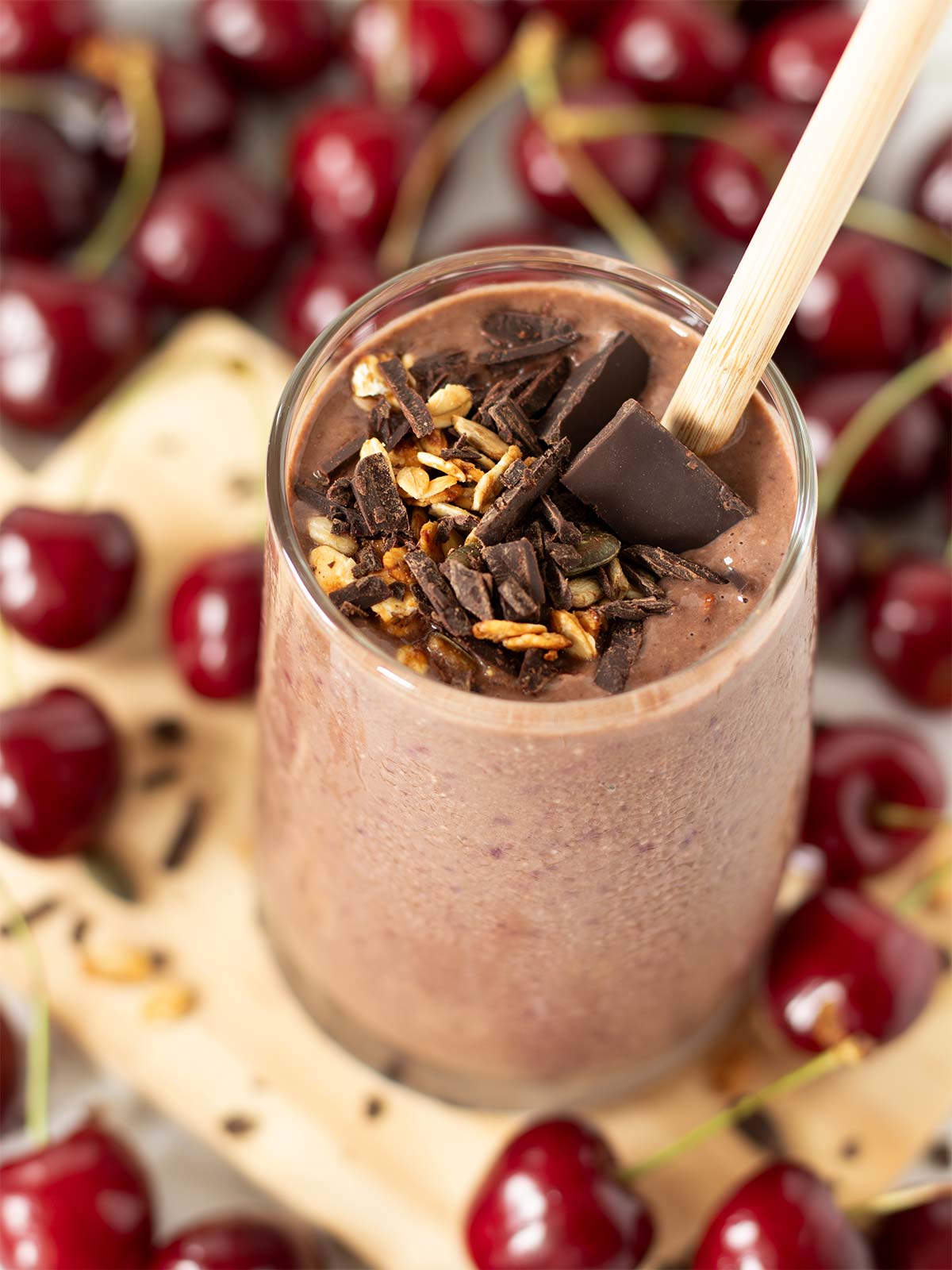 Chocolate cherry weight loss shake in a glass topped with granola and chopped dark chocolate