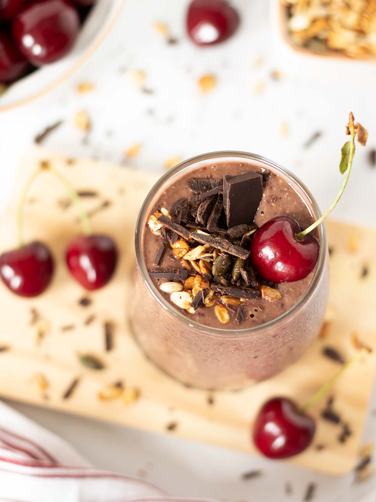 Chocolate cherry oat smoothie topped with granola and chopped dark chocolate