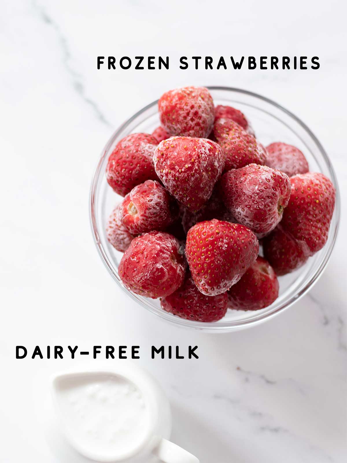 Frozen strawberries and coconut milk on white marbe table