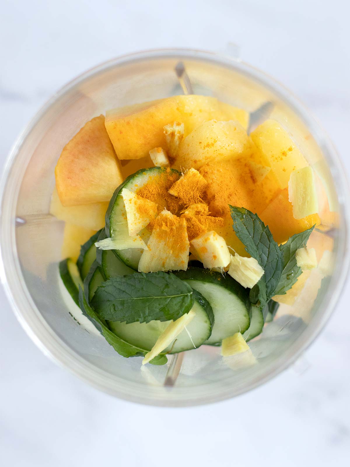 Detox ingredients in a blender cup for preparing creamy cucumber and pineapple smoothie for weight loss.