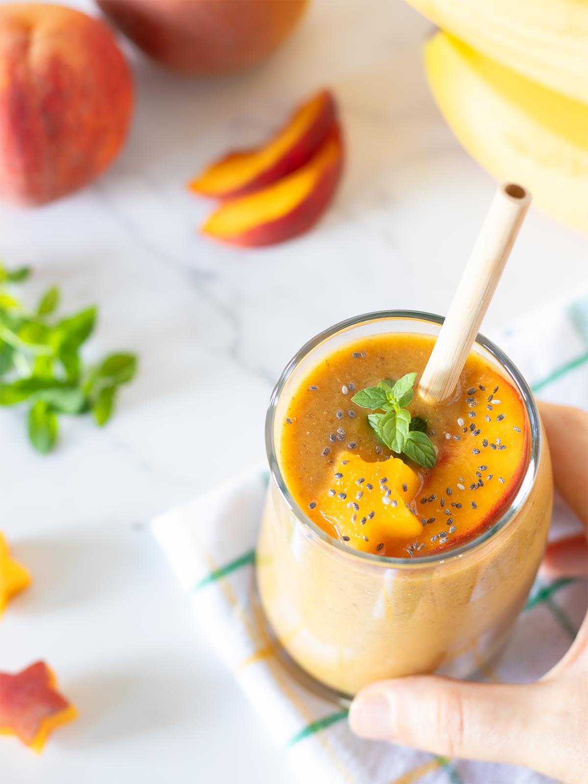 Peach banana smoothie without yogurt topped with fresh mint spring.