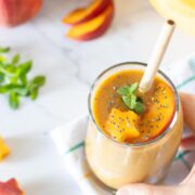 Peach banana smoothie without yogurt topped with fresh mint spring.