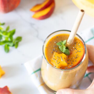 Peach banana smoothie without yogurt topped with fresh mint spring.