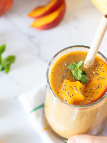 Peach banana smoothie without yogurt topped with fresh mint spring.