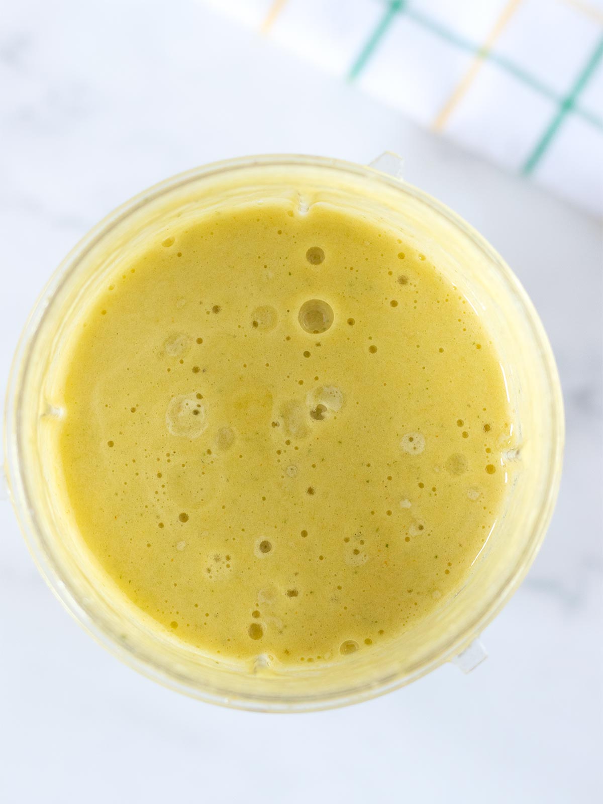 Freshly blended yellow pineapple turmeric smoothie with cucumber, peach, ginger and fresh mint.