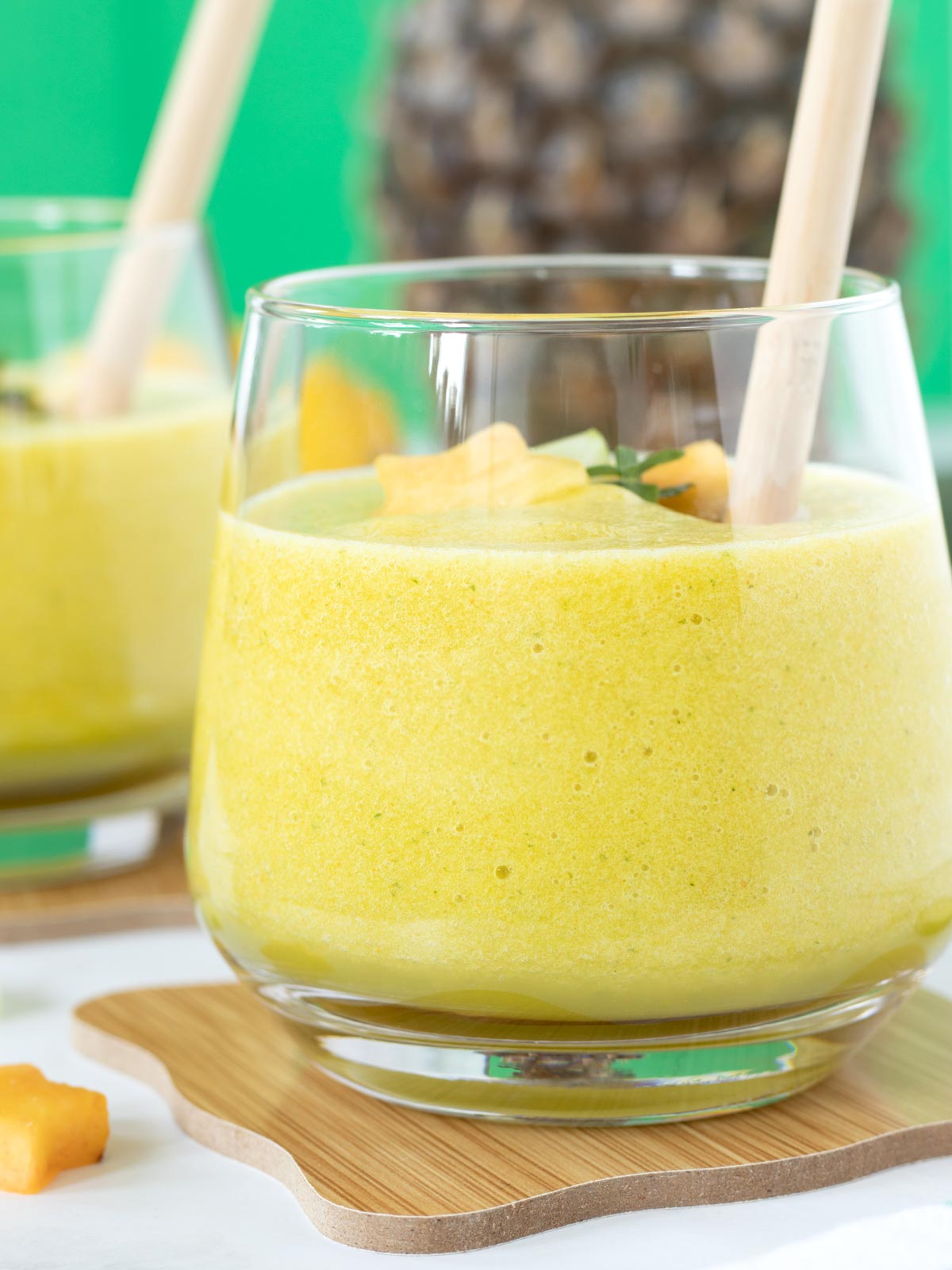 Fat-burning detox cucumber and pineapple smoothie with lemon, mint, and turmeric in a glass with bamboo straw.