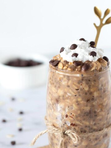 Healthy protein chocolate chip cookie dough overnight oats without yogurt topped with whipped cream in a glass.