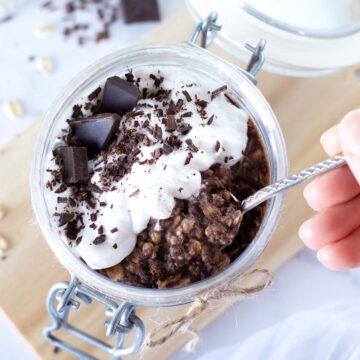 Chocolate protein overnight oats (proats) without yogurt in jar topped with whipped cream and chopped dark chocolate.