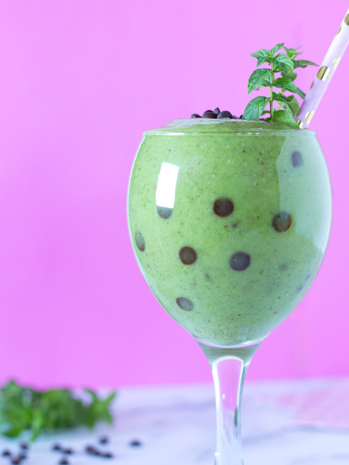 Green smoothie with mint leaves and vegan chocolate chips.